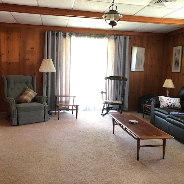 A cozy living room with a green armchair, a wooden coffee table, a rocking chair, and a leather sofa. - FernRockCabin- A Peaceful getaway in the Laurel Highlands of PA
(Farmington)