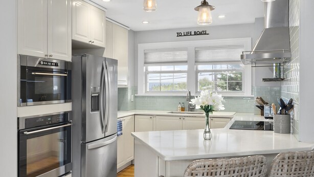 A modern kitchen with stainless steel appliances, a central island, and a view of the outdoors through large windows. - 3bed, 2bath Hamptons Home, Close to Incredible Beaches and Restaurants! (Hampton Bays)