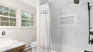 A bathroom with a shower, toilet, and sink.