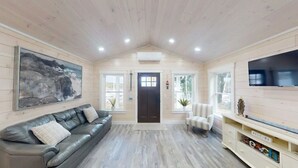 Un intérieur en bois avec un canapé en cuir, un téléviseur fixé au mur et une porte avec des fenêtres.