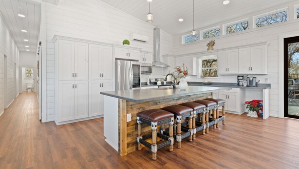 A spacious kitchen with white cabinetry, a central island with stools, and a large window providing natural light. - Welcome to our picturesque ranch oasis less than 1 hour from DFW!  (Cleburne)