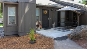 A modern house with a dark gray exterior, a front door, and a small patio area with a table and chairs. - Whitefish Condo w/ Pool Access + Close to Hiking! (Whitefish)