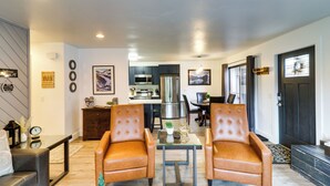 A modern living room with leather armchairs, a glass coffee table, and a kitchen in the background. - Whitefish Condo w/ Pool Access + Close to Hiking! (Whitefish)