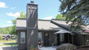 A modern building with a prominent chimney, a covered porch, and a landscaped front yard. - Whitefish Condo w/ Pool Access + Close to Hiking! (Whitefish)