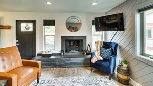 A modern living room with a fireplace, leather sofa, and a blue armchair. - Whitefish Condo w/ Pool Access + Close to Hiking! (Whitefish)