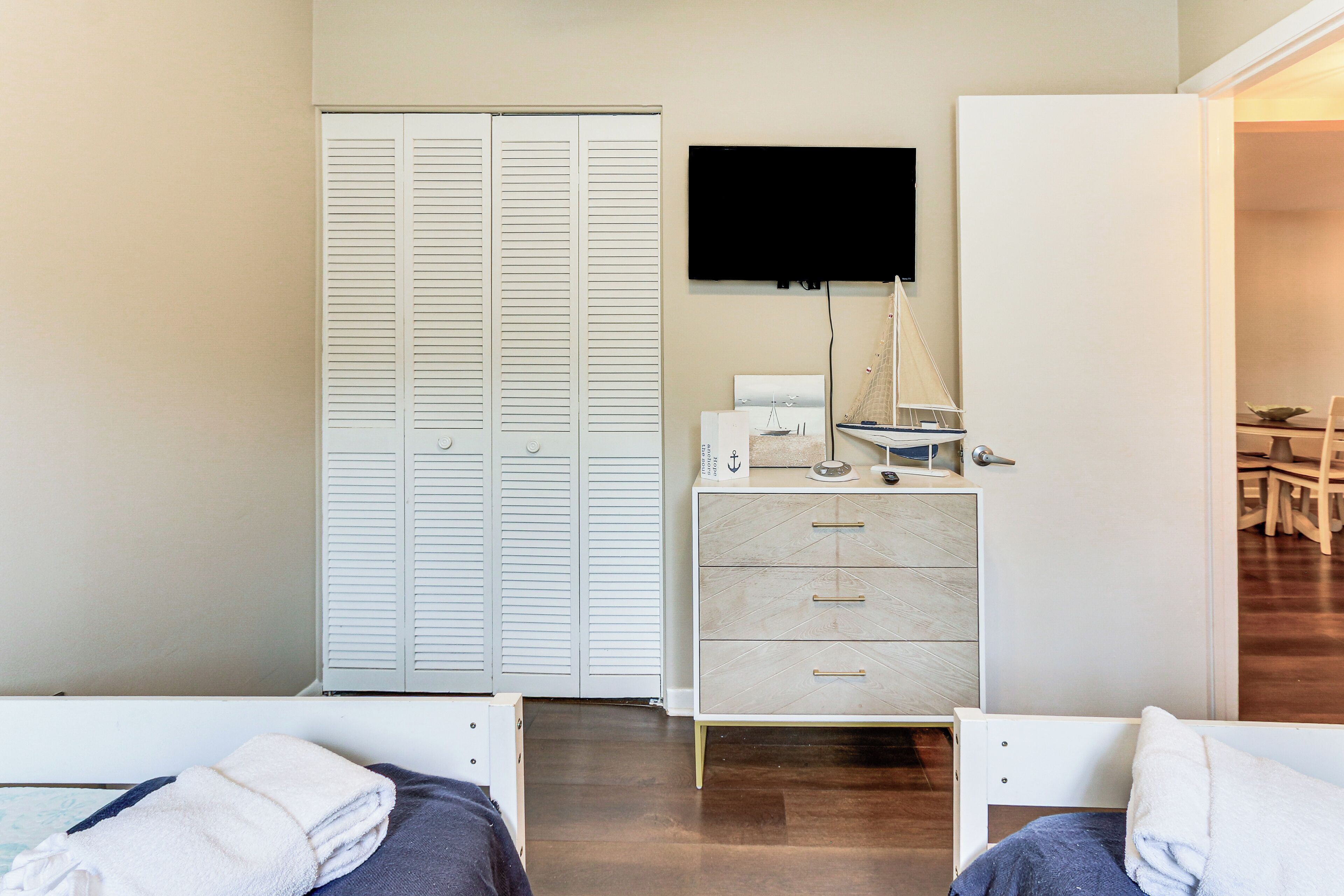 A bedroom with a bed, a dresser, a television, and a closet.