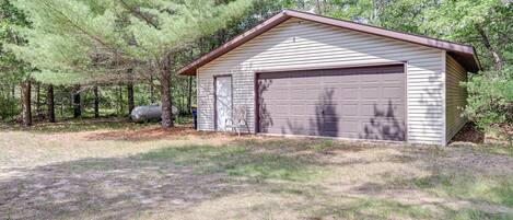 A single-story building with a garage, surrounded by trees and a grassy yard.