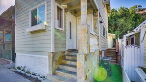 A house with a stone staircase leading to the front door, a small porch, and a fenced yard with artificial grass. - Avalon Cottage < Half-mi to Beaches & Crescent Ave (Avalon)