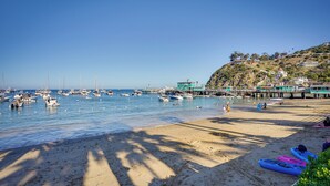 A beach with boats, a pier, and a hill with buildings. - Avalon Cottage < Half-mi to Beaches & Crescent Ave (Avalon)