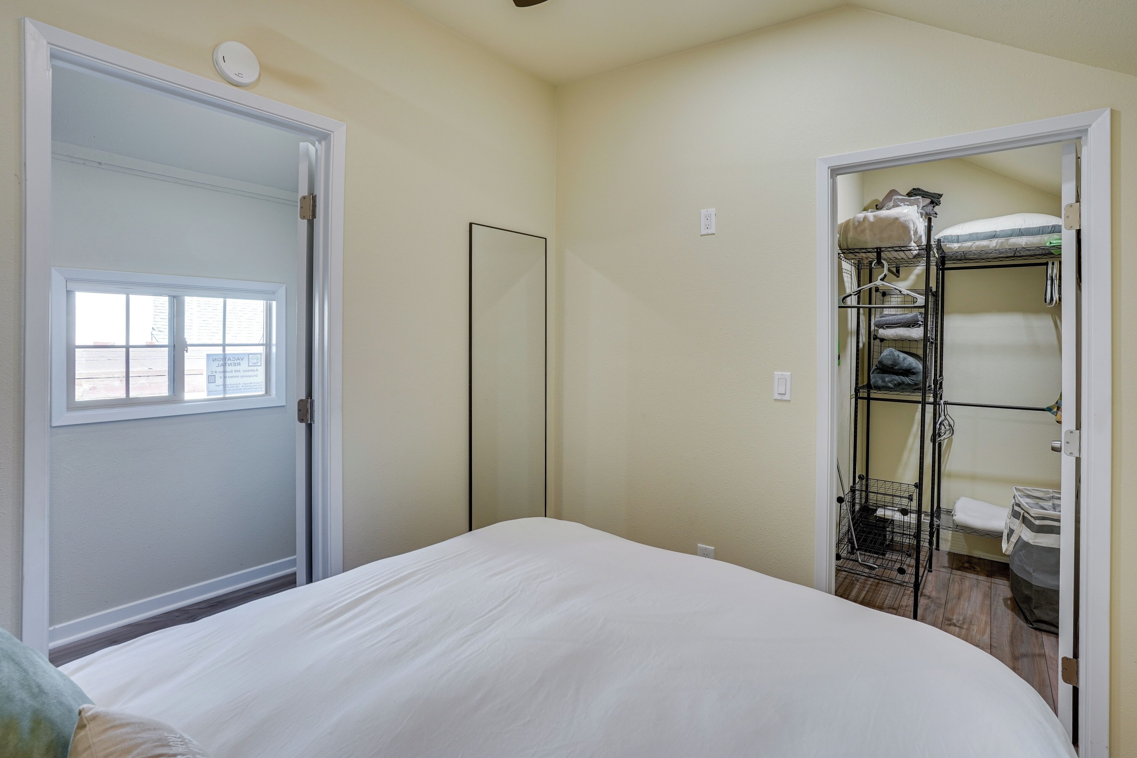 A bedroom with a bed, a closet with shelves, and a window.