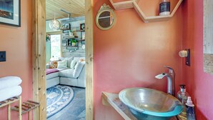 A bathroom with a large ceramic sink, wooden shelves, a mirror, and a hanging light fixture. - Yadkin River 'treehouse'~ Miles of Trails On-site (East Bend)