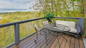 A wooden deck with a round table and two chairs, overlooking a forested landscape. - Yadkin River 'treehouse'~ Miles of Trails On-site (East Bend)