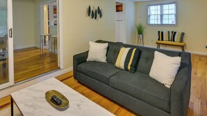 Un salon avec un canapé gris, une table basse blanche et une télécommande posée dessus.