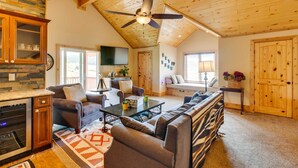 A spacious living room with a fireplace, a large sofa, a coffee table, and a ceiling fan. - Hot Tub & Fire Pit: Idyllic Getaway in Angel Fire! (Angel Fire)