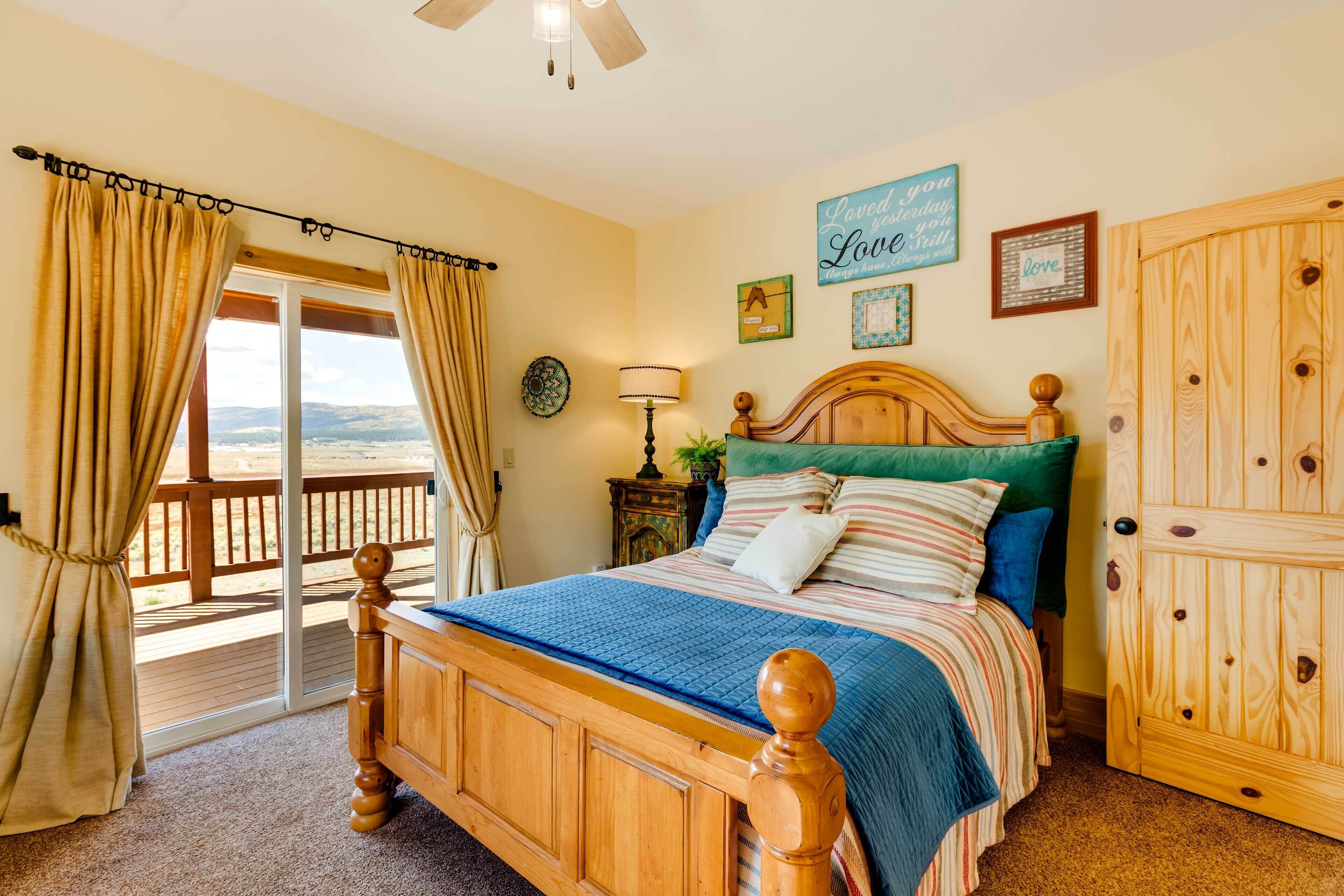 Un dormitorio con una cama de madera, vistas a través de un ventanal corredero, un armario de madera y una pared con un cartel que dice 'Loved you yesterday, love you today'.