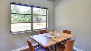 Un coin repas comprenant une table en bois, quatre chaises et une fenêtre donnant sur un jardin.