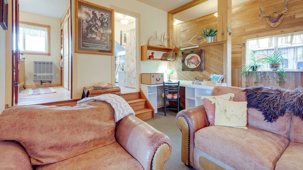 A cozy living room with leather sofas, a wooden desk, and a staircase leading to another room. - Charming Livingston Vacation Rental w/ Views! (Livingston)