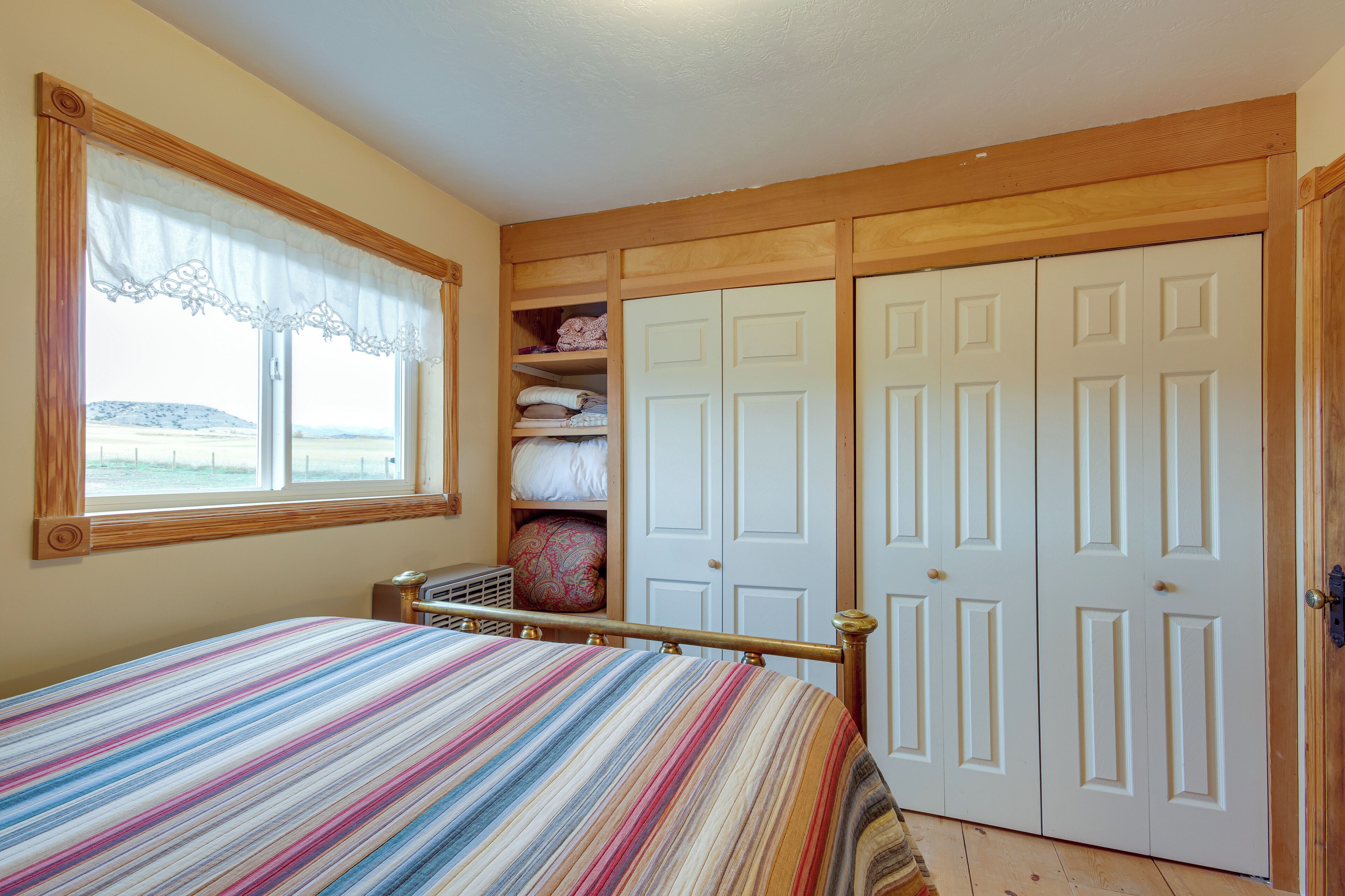 Ein Schlafzimmer mit Bett, Fenster mit Blick und Kleiderschrank.