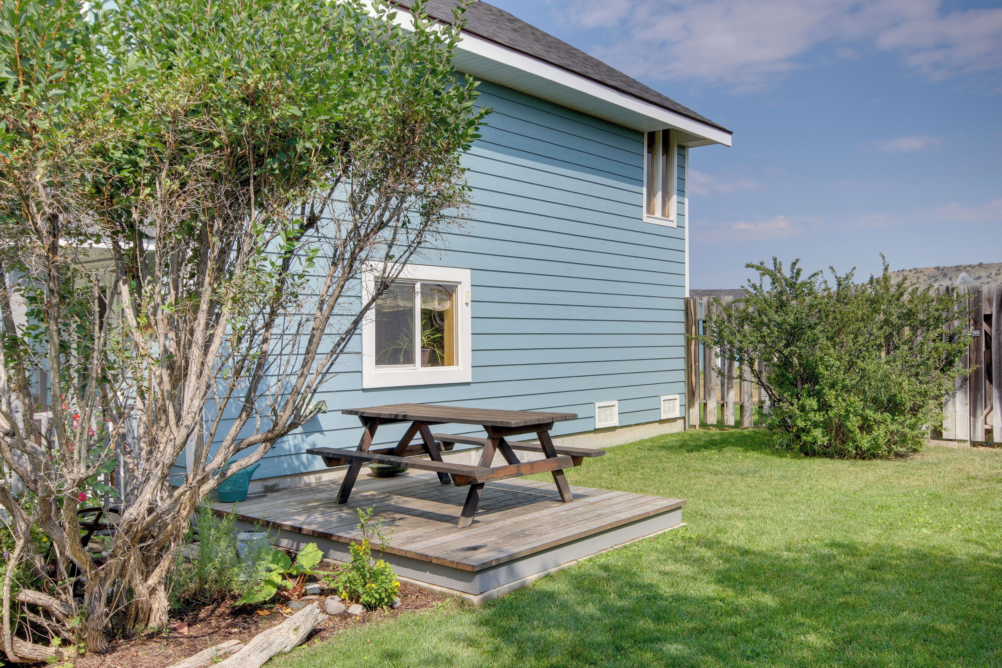 A house with a blue exterior, a wooden deck, and a picnic table.