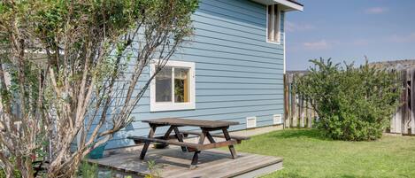 A house with a blue exterior, a wooden deck, and a picnic table.