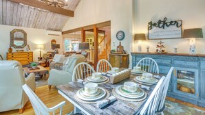 A dining area with a rustic wooden table set for four, surrounded by white chairs.