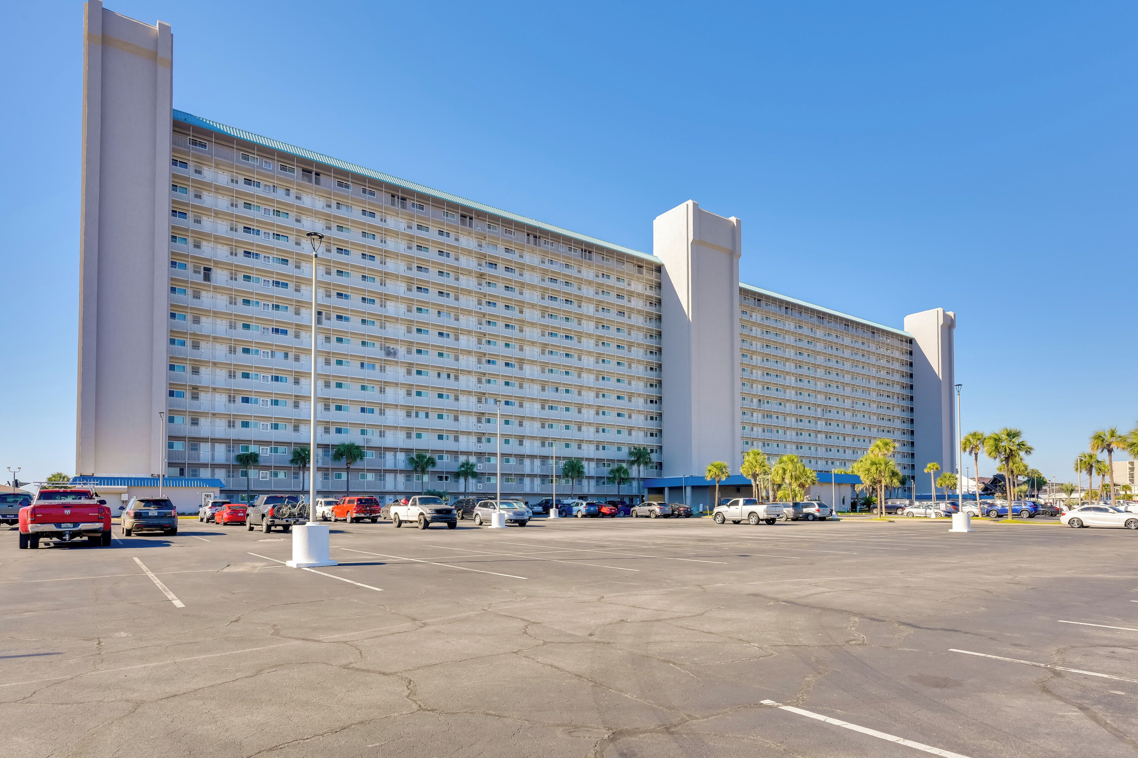 A large hotel with multiple floors and a parking lot in front.