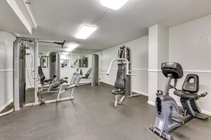 Una palestra con diverse attrezzature per esercizi, tra cui un tapis roulant, macchinari per pesi e una parete con specchi.