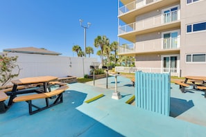 Zona patio esterna con tavoli da picnic e pavimento azzurro chiaro.