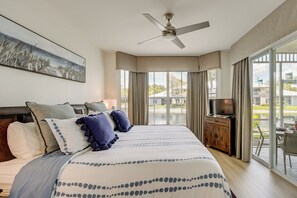 A bedroom with a bed, a ceiling fan, a TV, and a view of the outdoors. - Newly Updated Golf Villa w/ Free Golf May-oct (Naples)