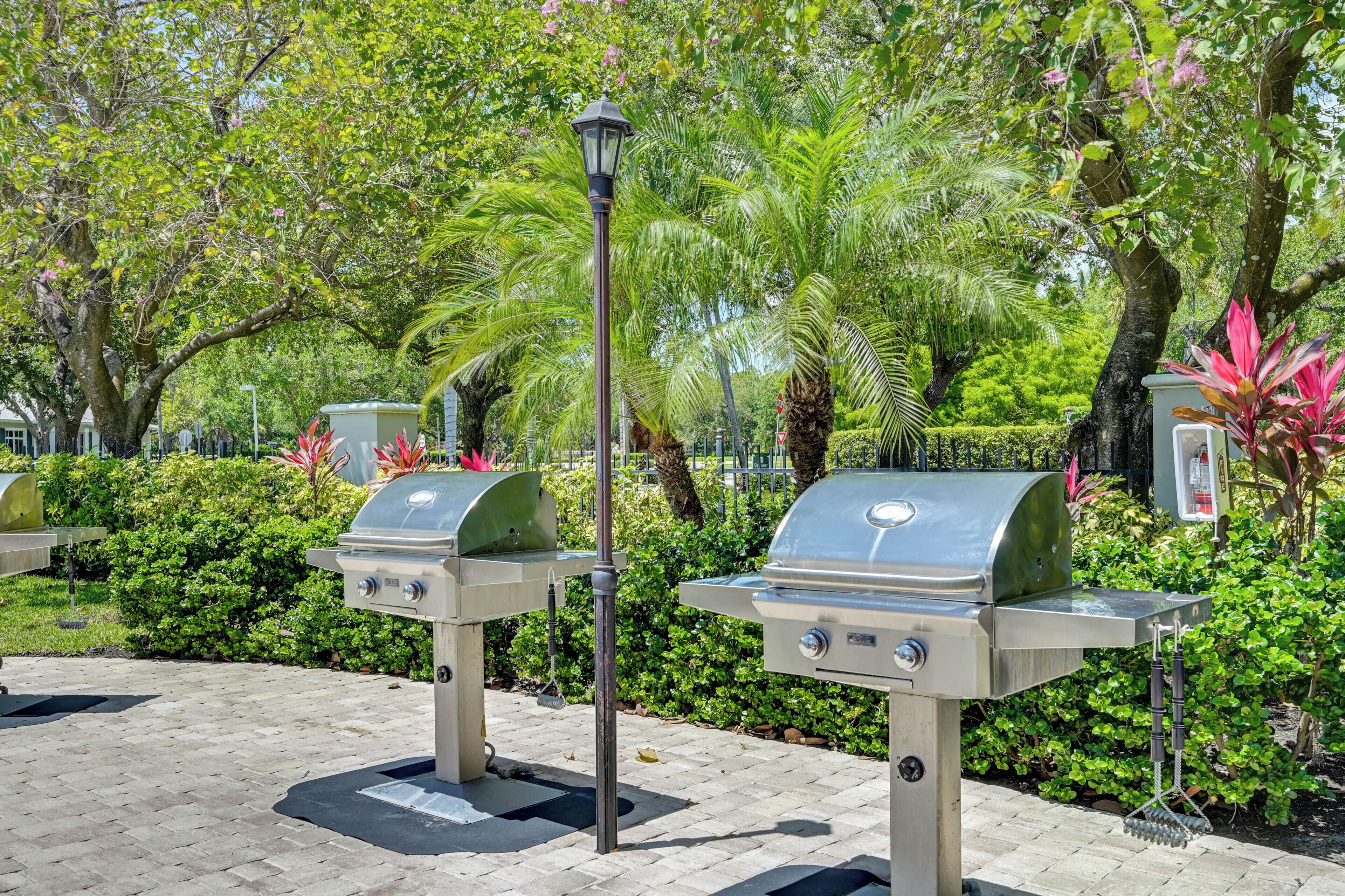 Buitenbarbecues, een lantaarnpaal en weelderige begroeiing in een park.