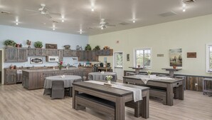 A spacious kitchen with wooden cabinets, a central island, and a dining area with tables and benches. - Family Reunions, Groups, 40 acres wide open spaces (Concho)