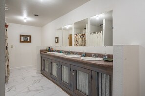 Un bagno con due lavabi, uno specchio grande e un armadietto con tende.