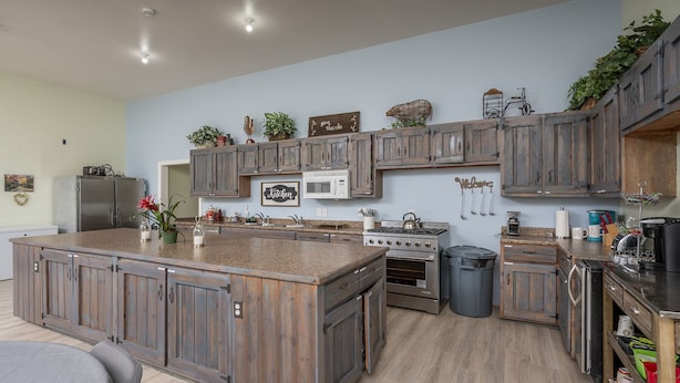 A kitchen with wooden cabinets, a central island, a stove, and various kitchen appliances. - Family Reunions, Groups, 40 acres wide open spaces (Concho)
