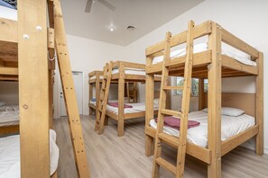 Una camera con letti a castello, mobili in legno e una ventola a soffitto.