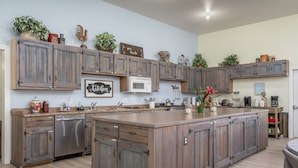 A spacious kitchen with wooden cabinets, a central island, and various kitchen appliances. - Family Reunions, Groups, 40 acres wide open spaces (Concho)