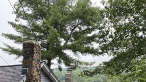 A house with a stone chimney, a dock extending into a lake, and a wooden deck. - Serene 2-bedroom, 2-bath lakefront retreat on scenic Staffordville Lake (Stafford)