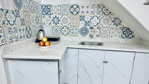 A kitchen with white cabinets, a marble countertop, and a backsplash with blue and white tiles.