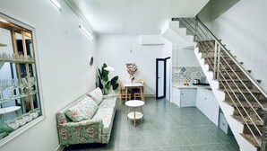 A modern living room with a sofa, a dining table, and a staircase.