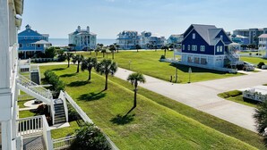 Una zona residencial costera con varias casas azules, un césped bien cuidado y una vista despejada del océano.