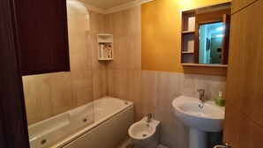 Un baño con bañera, bidé, inodoro y lavamanos.