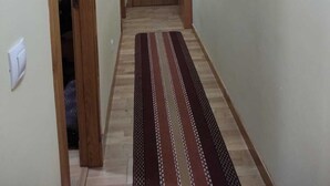 Un pasillo con puerta de madera, alfombra estampada y obras de arte en las paredes.