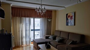 Una sala de estar con un sofá, una mesa de centro, una araña y un cuadro en la pared.