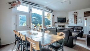 Un salón amplio con chimenea, televisor grande y vistas al exterior.