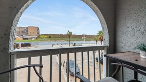 A balcony with a view of a parking lot and a building in the distance. - Cozy Studio Loft | Indoor Pool & Walk to Beach (Corpus Christi)