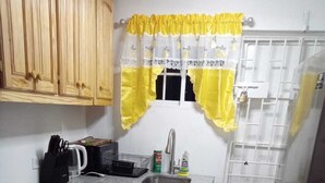 A compact kitchen with wooden cabinets, a sink, a microwave, and a fan.