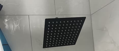 A bathroom with white tiles, a black shower head, and cartoon character decorations.