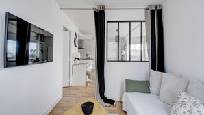 A modern living room with a sofa, a coffee table, and a view of the city through large windows. - Appartement de Charme Hypercentre Brest (Brest)