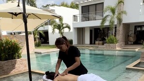 Una persona recibiendo un masaje junto a una piscina.