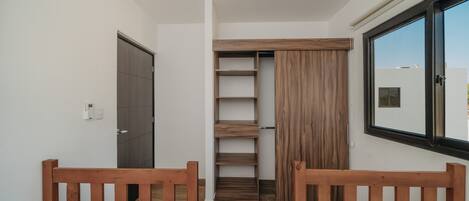 A bedroom with two wooden beds, a wardrobe, and a window.