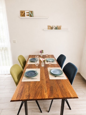 Une table à manger dressée avec des assiettes, des verres et un vase rempli de fleurs.